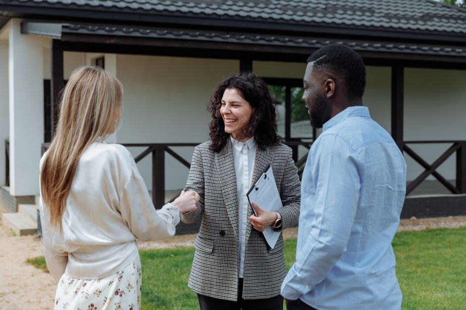 A young couple stands thoughtfully looking at the exterior of a modern suburban home, representing homebuyers navigating the current New Jersey real estate market.